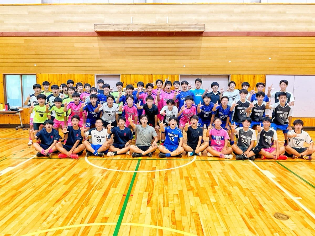 体育館の床に並んだ部員と指導者の記念撮影